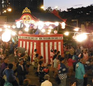 Bon dance at dusk around an ornate, red-and-white-striped central stage