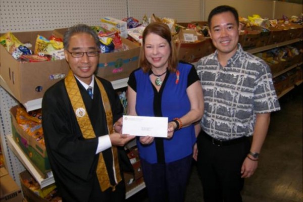 Polly Kauahi, Vice President and Chief Operating Officer of Hawaii Food Bank, receives the Mission's donation from Bishop Eric Matsumoto and Blayne Higa, HHMH Social Concerns Committee Chair. Photo courtesy of Hawaii Food Bank.
