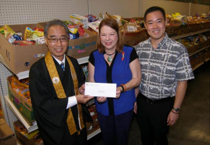 Polly Kauahi, Vice President and Chief Operating Officer of Hawaii Food Bank, receives the Mission's donation from Bishop Eric Matsumoto and Blayne Higa, HHMH Social Concerns Committee Chair. Photo courtesy of Hawaii Food Bank.
