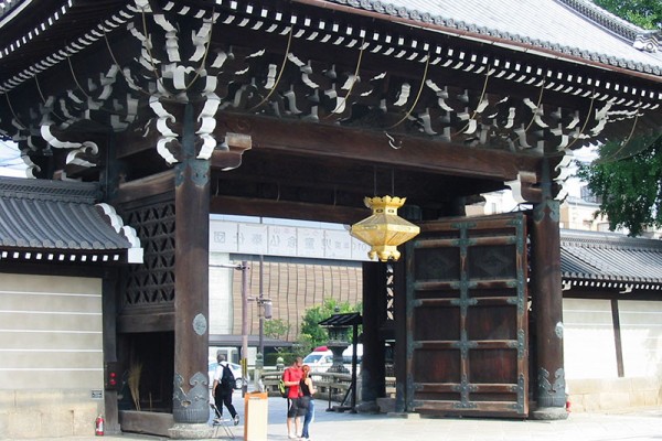 giant gate to Nishi Hongwanji in Kyoto with gold lamp and doors open
