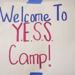 sign reading "Welcome to YESS Camp!" taped to a building
