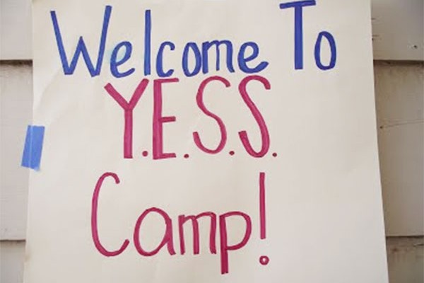sign reading "Welcome to YESS Camp!" taped to a building