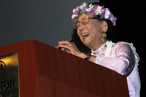 Lillian Noda Yajima with haka lei laughs at the podium