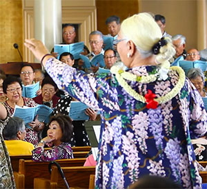 woman wearing lei conducting choir at Hawaii Betsuin