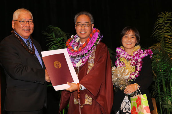 Pieper Toyama presents certificate to Bishop Eric Matsumoto with Mrs. Tamayo Matsumoto at right