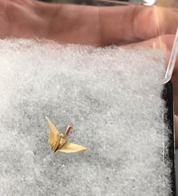 closeup of tiny, gold paper crane folded by Sadako Sasaki