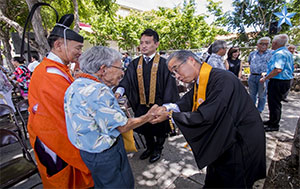 Bishop Matsumoto shakes hand of Hiroshima bombing survivor Lawrence Fumio Miwa. Star-Advertiser photo, see https://www.staradvertiser.com/2019/08/06/photo-gallery/30th-annual-hiroshima-commemoration-and-peace-service-ceremony/