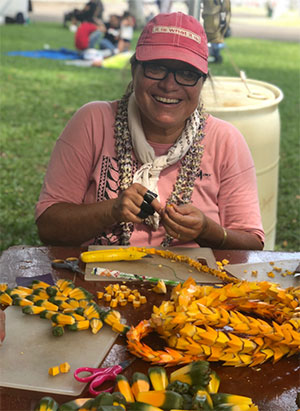 Dr. Manulani Aluli Meyer smiling in park with cap and lei
