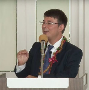 Duncan Williams wearing lei gestures at the podium