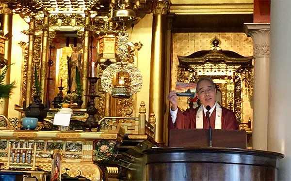 Bishop Matsumoto holds up a card with a sunset during a talk at Hawaii Betsuin