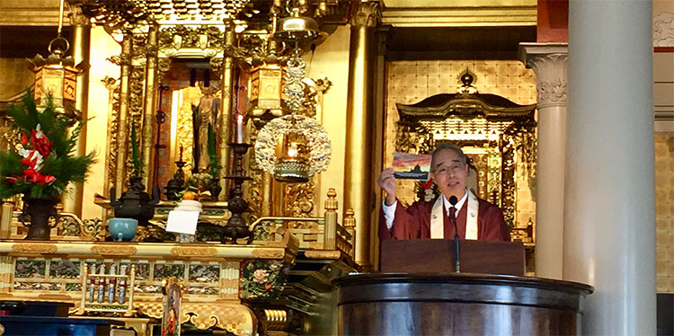Bishop Matsumoto holds up a card with a sunset during a talk at Hawaii Betsuin