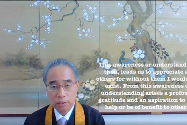 still image of Bishop Matsumoto from his April 2020 video message with Japanese art in the background