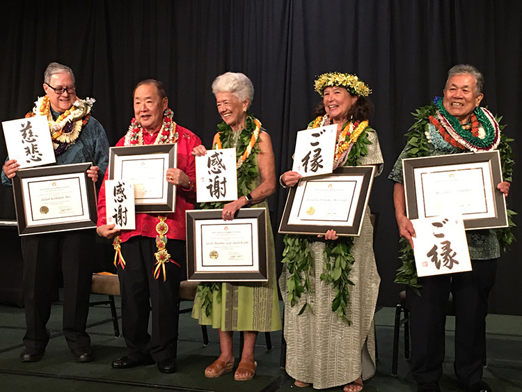 Living Treasures 2024 - closer view of honorees on stage with lei, calligraphy, and certificates