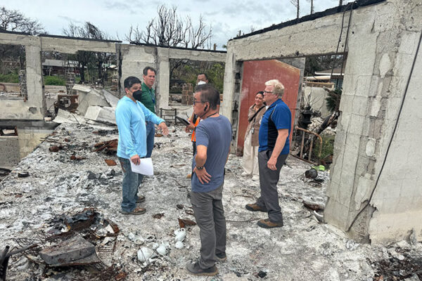 Derrick Inouye, holding paperwork, gestures to FEMA officials in the ruins of Lahaina Hongwanji in March 2024