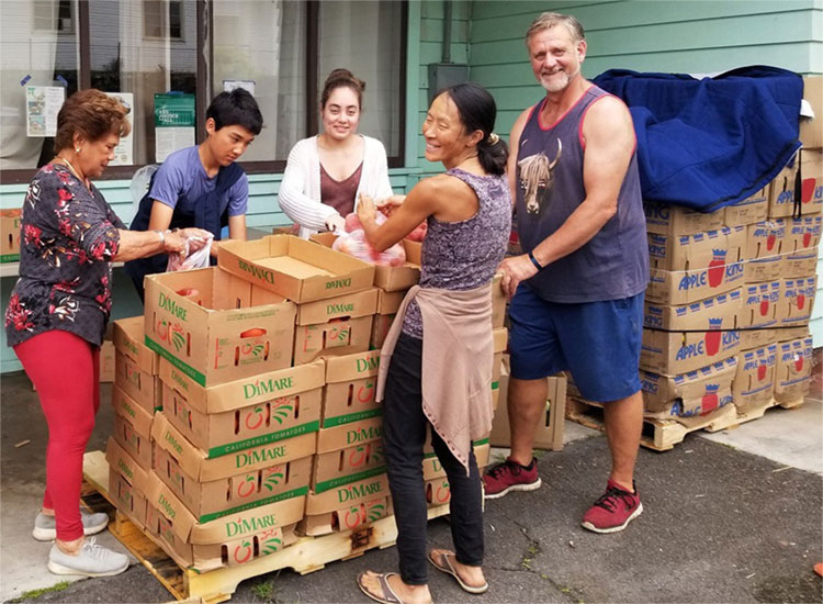 Sangha members pack cardboad boxes with food.